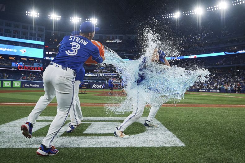 Myles Straw (3) y Vladimir Guerrero Jr. (27), de los Azulejos de Toronto, dan un baño con Gatorade a Davis Schneider (36) después una victoria contra los Yankees de Nueva York tras la victoria en el juego de béisbol de Grandes Ligas, el miércoles 2 de julio de 2025. (Sammy Kogan/The Canadian Press vía AP)
