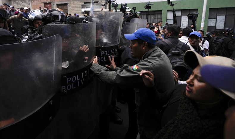 Seguidores del expresidente Evo Morales empujan los escudos de los policías fuera de una comisaría, en La Paz, Bolivia, el jueves 14 de noviembre de 2024, en una protesta contra la detención de dos dirigentes afines al exmandatario por los bloqueos de carreteras. (AP Foto/Juan Karita)