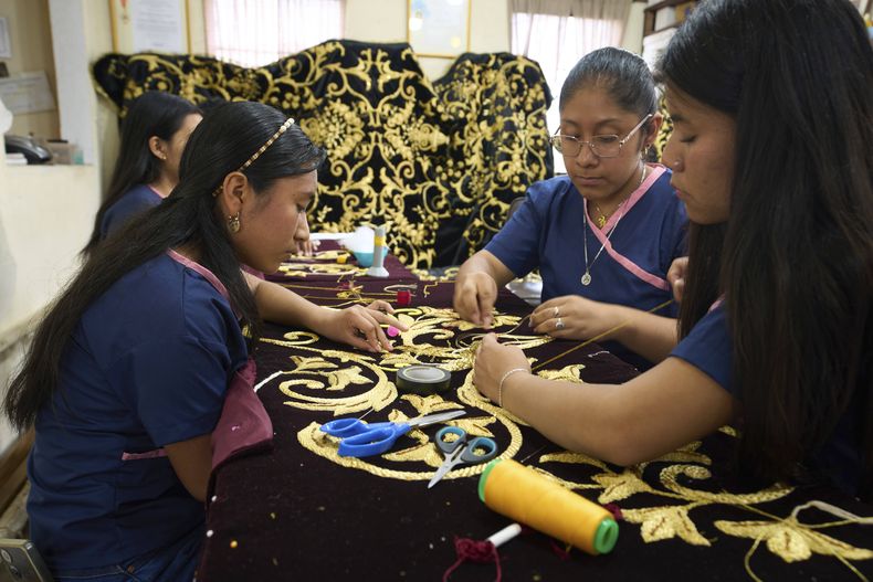 Varias costureras pones piezas doradas a la túnica que llevará la imagen de la Virgen María, en el taller de bordado María Auxiliadora en San Miguel Escobar, Guatemala, el miércoles 2 de abril de 2025. (AP Foto/Moisés Castillo)