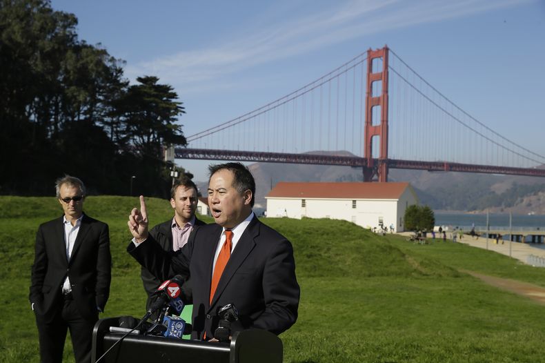 El legislador estatal Phil Ting (en el podio) habla en contra del plan de cobrarle cuota a los peatones y ciclistas que crucen el puente Golden Gate (al fondo), durante una conferencia de prensa el martes 25 de noviembre de 2014, en Crissy Field, San Fran