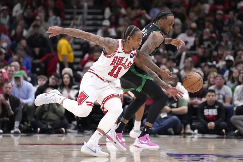 DeMar DeRozan (11), de los Bulls de Chicago, y Oshae Brissett, de los Celtics de Boston, persiguen un balón suelto durante la segunda mitad de un partido de baloncesto de la NBA, el sábado 23 de marzo de 2024, en Chicago. Los Celtics ganaron 124-113. (AP Foto/Charles Rex Arbogast)