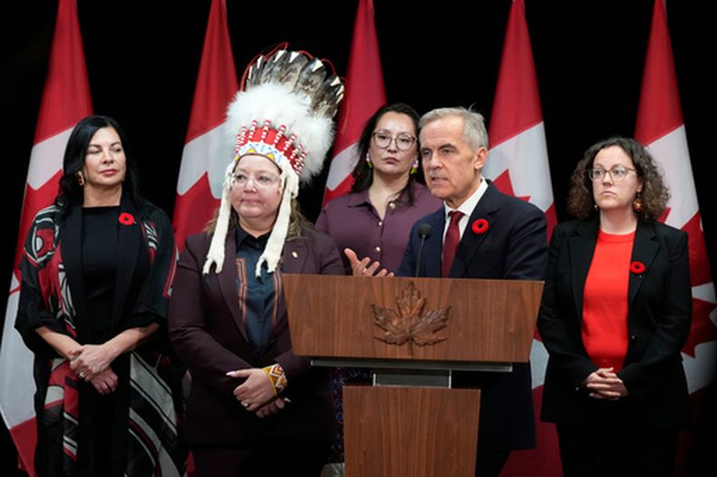 De izquierda a derecha, la ministra para Asuntos del Norte y el Ártico Rebecca Chartrand, la jefa nacional de la AFN Cindy Woodhouse Nepinak,la ministra de Asuntos Indígenas Mandy Gull-Masty y la ministra de Relaciones entre Indígenas y la Corona, Rebecca Alty, acompañan en el estrado al primer ministro de Canadá, Mark Carney, durante un encuentro, el lunes 26 de octubre de 2026, en Ottawa. (Adrian Wyld/The Canadian Press via AP)