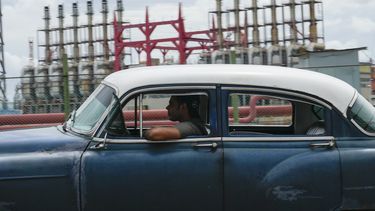 Una persona conduce un automóvil clásico estadounidense junto a un generador flotante que no produce electricidad desde hace días en La Habana, Cuba, el viernes 18 de octubre de 2024. (AP Foto/Ramón Espinosa)