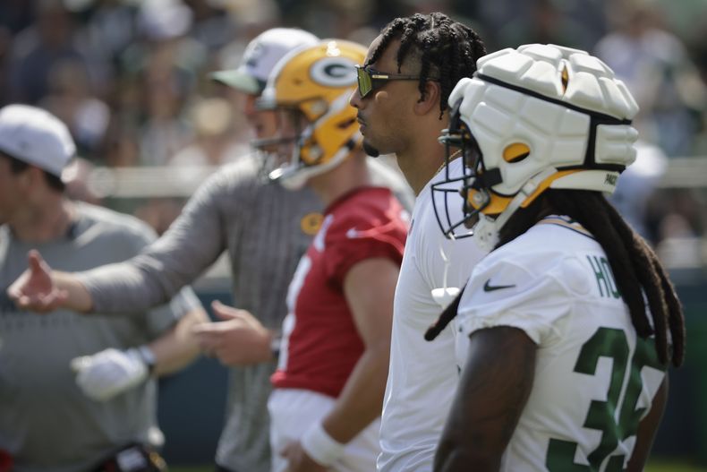 Jordan Love (con lentes), quarterback de los Packers de Green Bay, observa el entrenamiento durante el primer día del campo de entrenamiento, el lunes 22 de julio de 2024, en Green Bay, Wisconsin. Los Packers dijeron que Love no entrenará hasta que no firme un nuevo contrato. (AP Foto/Mike Roemer)