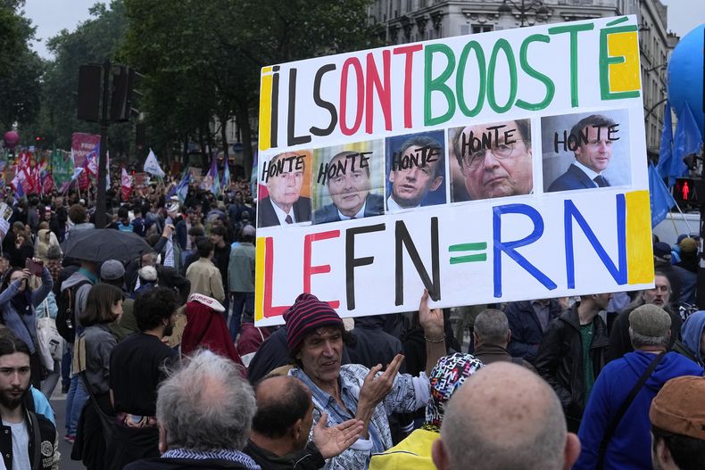 Un manifestante sostiene un letrero contra la derecha que muestra los rostros de expresidentes franceses y del actual presidente Emmanuel Macron con la palabra Vergüenza durante una protesta en París, el sábado 15 de junio de 2024. (AP Foto/Michel Euler)