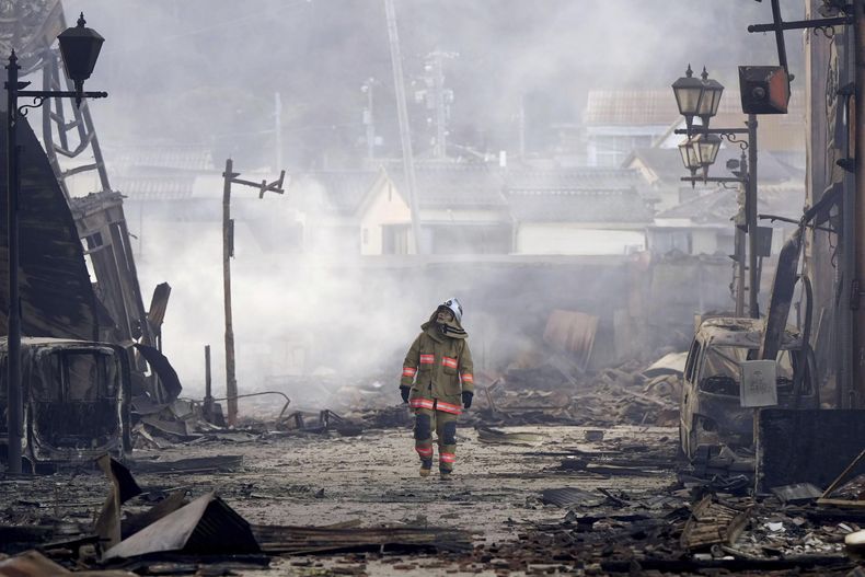 Un bombero camina entre los escombros y los restos de un incendio en un mercado, luego de un terremoto, en Wajima, en la prefectura de Ishikawa, Japón, el 2 de enero de 2024. (Kyodo News vía AP)