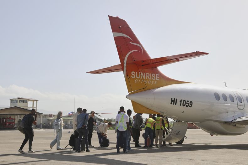 Un grupo de pasajeros espera abordar un avión de Sunrise Airways en el aeropuerto Guy Malary de Puerto Príncipe, Haití, el jueves 12 de junio de 2025. (AP Foto/Odelyn Joseph)