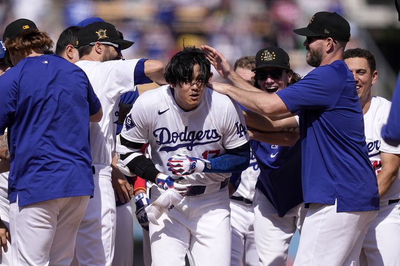 Shohei Ohtani, centro, de los Dodgers de los Ángeles, es felicitado por sus compañeros de equipo después de batear un sencillo para dejar tendidos a los Rojos de Cincinnati en la 10ma entrada del juego de béisbol, el domingo 19 de mayo de 2024, en Los Ángeles. Los Dodgers ganaron 3-2. (AP Foto/Mark J. Terrill)