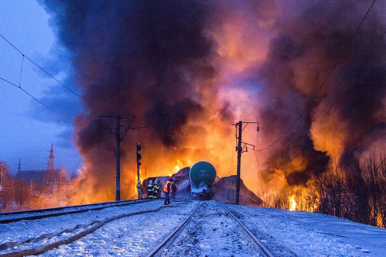 En esta fotograf&iacute;a proporcionada por el servicio de prensa del Ministerio de Situaciones de Emergencia de Kirov, bomberos y empleados del ministerio observan carros ciesterna incendiados tras el descarrilamiento de un tren, el mi&eacute;rcoles 5 de