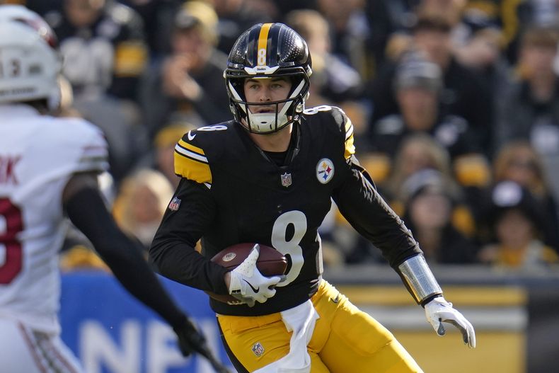 ARCHIVO - Kenny Pickett (8), quarterback de los Steelers de Pittsburgh, trata de eludir la presión saliendo de la bolsa de protección ante la mirada de KeiTrel Clark (13), cornerback de los Cardinals de Arizona durante la primera mitad del juego de la NFL, el domingo 3 de diciembre de 2023. Los Steelers están intercambiando a Pickett a los Eagles, dijo una persona con conocimiento del acuerdo a The Associated Press el viernes 15 de marzo de 2024. (AP Foto/Gene J. Puskar, Archivo)
