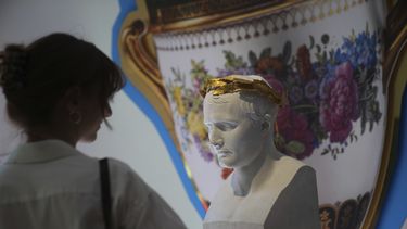 Una mujer observa un busto de Napoleón en una exposición de pertenencias de Napoleón creada por el diseñador francés Jean-Charles de Castelbajac en la casa de subastas Sothebys en París el jueves 19 de junio de 2025 en París. (Foto AP/Christophe Ena)