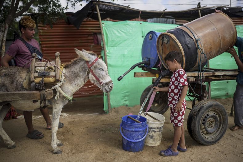 Un niño llena un cubo de agua transportada por mulas en el barrio La Voz que Clama, en las afueras de Maicao, Colombia, el miércoles 5 de febrero de 2025. (AP Foto/Ivan Valencia)