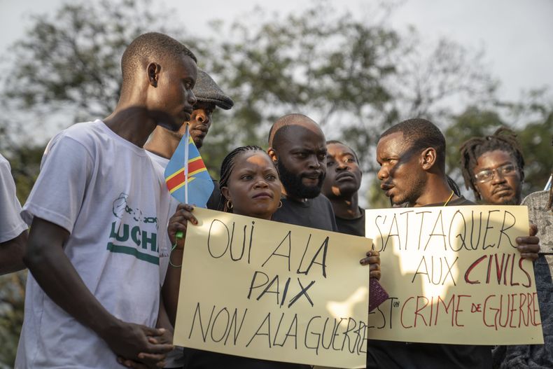 Varias personas se reúnen en Goma, en la República Democrática del Congo, el lunes 6 de mayo de 2024 para honrar a las víctimas del ataque contra el campamento de Mugunga perpetrado días antes. Los carteles dice: Sí a la paz, no a la guerra y Atacar civiles es un crimen de guerra. (AP Foto/Moses Sawasawa)