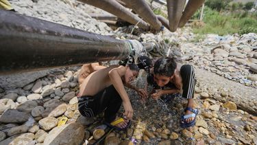 Niños tratan de refrescarse con agua que sale de un ducto en medio del calor en Jammu, India, el 10 de junio del 2025. (AP foto/Channi Anand)