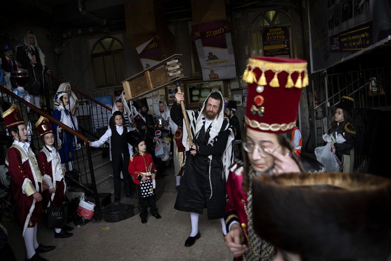 ARCHIVO - Hombres y niños ultraortodoxos judíos, algunos con disfraces, festejan Purim en una sinagoga en Bnei Brak, Israel, 17 de marzo de 2022. Purim celebra la historia bíblica de cómo se frustró un complot para exterminar a los judíos en Persia y, por lo tanto, es considerada una afirmación de la supervivencia judía a lo largo de la historia. (AP Foto/Oded Balilty, File)