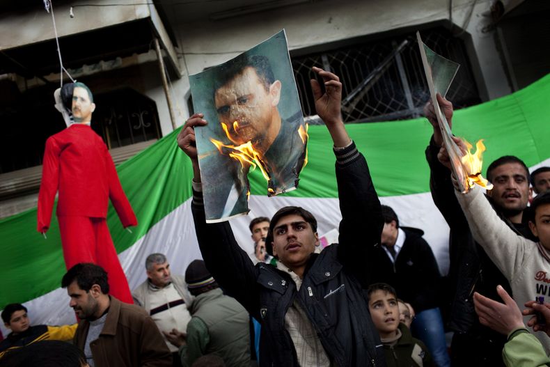 Fotograf&iacute;a de archivo del 26 de febrero de 2012, de personas quemando retratos del presidente sirio, Bashar Assad, durante una manifestaci&oacute;n contra su gobierno en las afueras de Idlib, Siria. (Foto AP/Rodrigo Abd, Archivo)