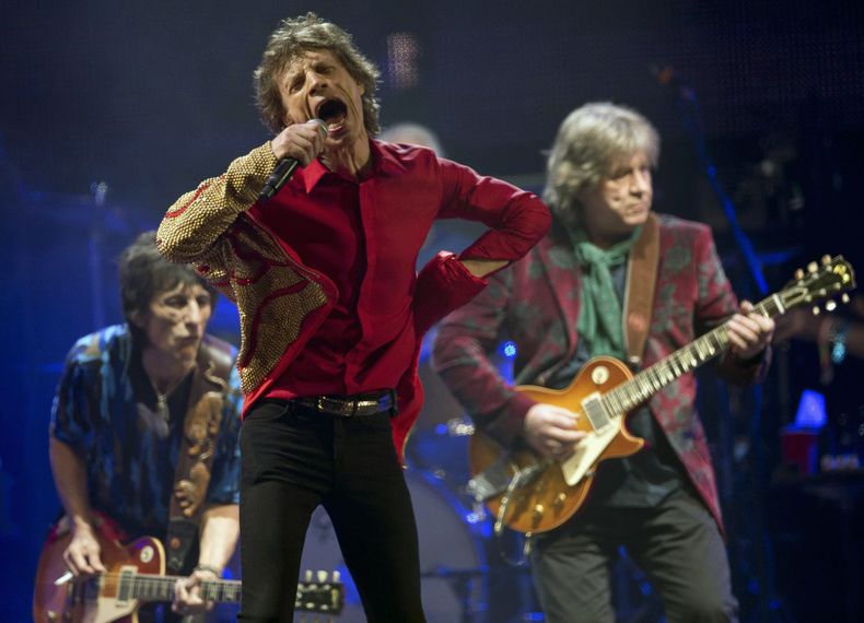 ARCHIVO - Mick Jagger, en el centro, Ronnie Wood, a la izquierda, y Mick Taylor, de la banda de rock británica The Rolling Stones, actúan en el escenario principal de la Pirámide en Glastonbury, Inglaterra, el 29 de junio de 2013. (Joel Ryan/Invision/AP, archivo)