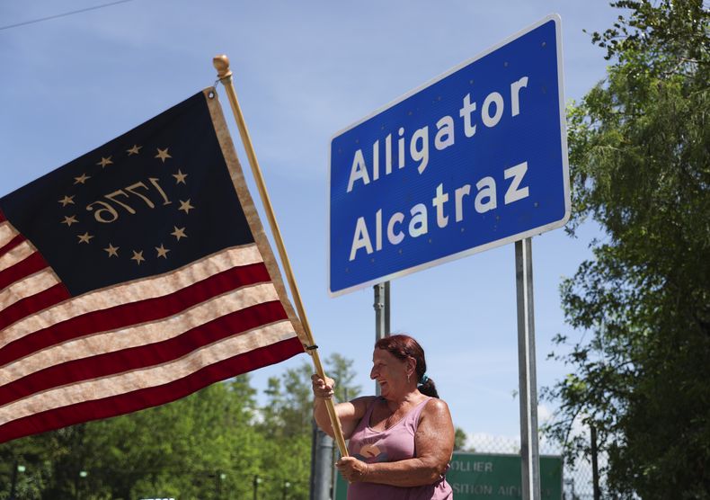Rana Mourer ondea una bandera estadounidense fuera del centro de detención de inmigrantes conocido como “Alcatraz de los Caimanes” en la instalación de Entrenamiento y Transición de Dade-Collier, el sábado 12 de julio de 2025 en Ochopee, Florida. (AP Foto/Alexandra Rodriguez)