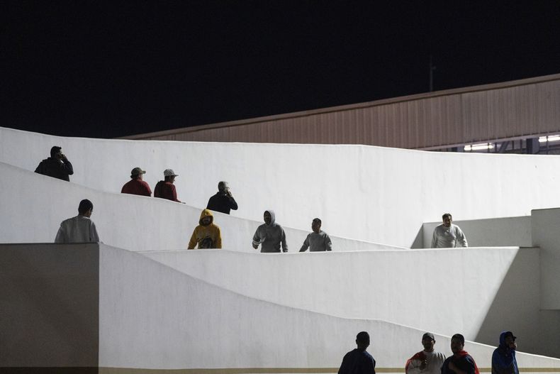 Migrantes entran a pie a México tras haber sido deportados desde Estados Unidos, en el paso peatonal de El Chaparral, en Tijuana, México, el 21 de enero de 2025. (AP Foto/Felix Marquez)