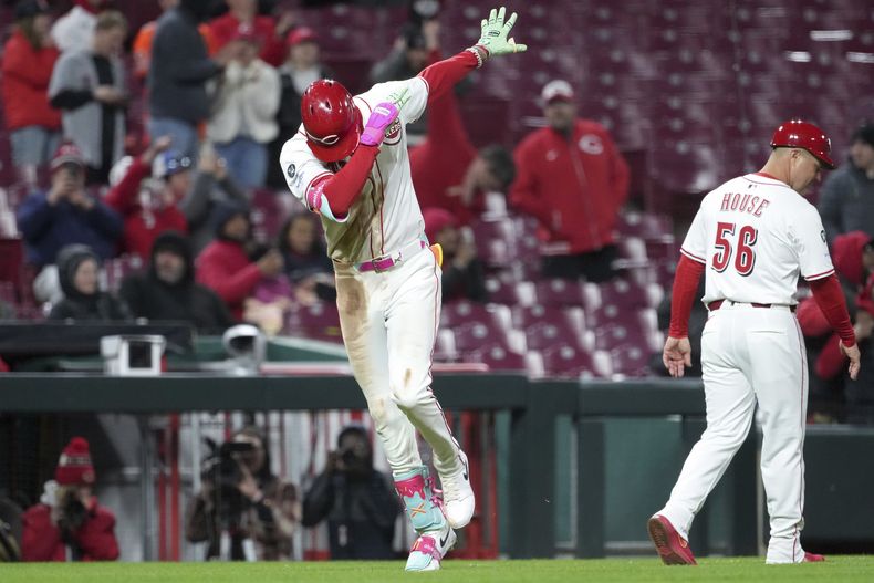 Elly De La Cruz, izquierda, de los Rojos de Cincinnati, celebra con el coach de tercera base J.R. House (56) después de batear un jonrón de dos carreras en la séptima entrada frente a los Rangers de Texas, el lunes 31 de marzo de 2025, en Cincinnati. (AP Foto/Kareem Elgazzar)