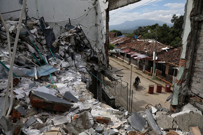 Un hombre pasa en motocicleta junto a las ruinas de casas destruidas cinco meses antes en un ataque de disidentes de las antiguas Fuerzas Amadas Revolucionarias de Colombia, o FARC, en Buenos Aires, Cauca, Colombia, el miércoles 20 de mayo de 2026.(AP Foto/Santiago Saldarriaga)