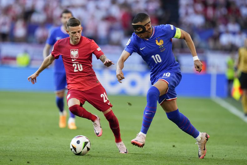 El francés Kylian Mbappé pasa el balón frente al polaco Sebastian Szymanski en el encuentro del Grupo D de la Eurocopa el martes 25 de junio del 2024. (AP Foto/Hassan Ammar)