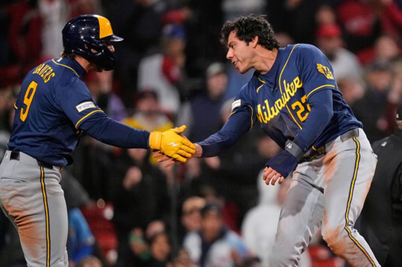 Christian Yelich de los Cerveceros de Milwaukee felicitado por Jake Bauers tras anotar en un sencillo de Garrett Mitchell en la octava entrada ante los Medias Rojas de Boston el lunes 6 de abril del 2026. (AP Foto/Charles Krupa)