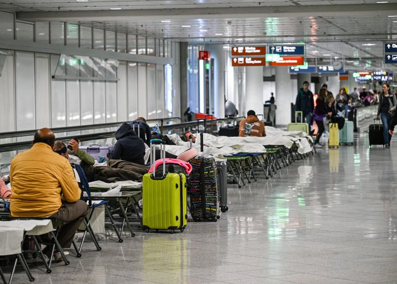 Varias personas esperan en catres en el aeropuerto de Múnich tras avistamiento de drones que cancelaron salidas de vuelos, en Múnich, Alemania, el 3 de octubre de 2025. (Jason Tschepljakow/dpa vía AP)