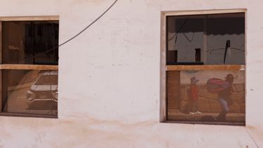 Varias personas caminan por la calle, una de ellas, con un paquete hecho de fibra textil sobre sus hombros, en la región de Chincheros en el Valle Sagrado cerca de Cusco, Perú, el sábado 30 de agosto de 2025. (AP Foto/Alie Skowronski)