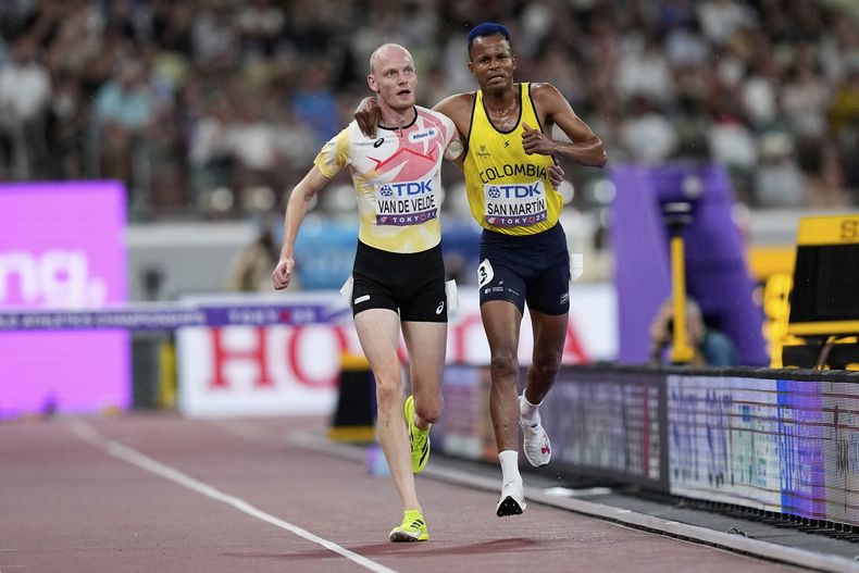 Carlos San Martín, de Colombia, recibe ayuda del belga Tim van de Velde, para concluir los 3.000 metros steeplechase en el Mundial de atletismo, el sábado 13 de septiembre de 2025 (AP Foto/Petr David Josek)