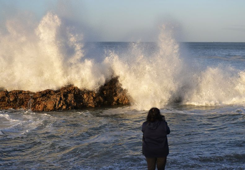 Una mujer fotografía las olas en Puerto Elizabeth, Sudáfrica, el domingo 17 de septiembre de 2023. (AP Foto/Deon Ferreira)