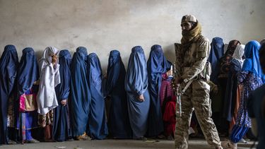 ARCHIVO - Un combatiente talibán vigila mientras mujeres esperan recibir raciones de comida distribuidas por un grupo de ayuda humanitaria en Kabul, Afganistán, el 23 de mayo de 2023. (AP Foto/Ebrahim Noroozi, Archivo)
