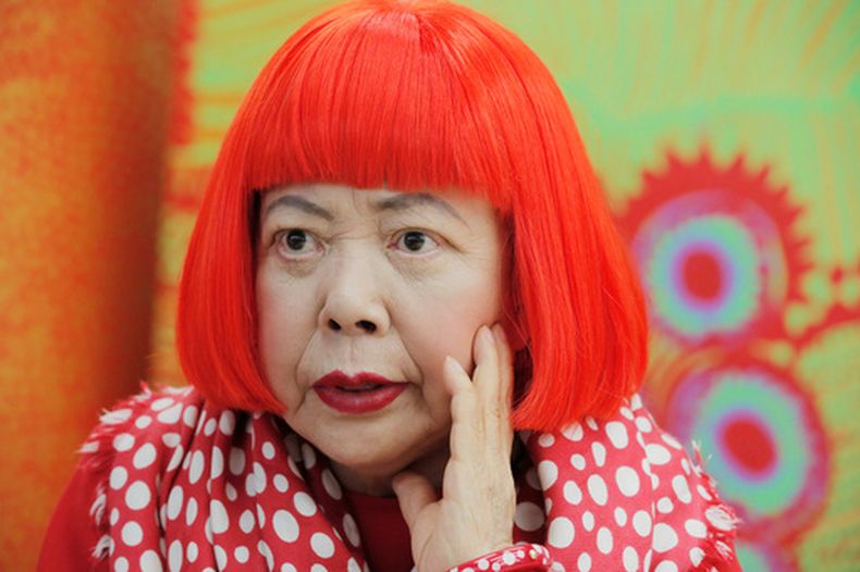 ARCHIVO - La artista japonesa Yayoi Kusama, con una peluca de color rojo brillante y un pañuelo de puntos de Louis Vuitton al cuello, durante una entrevista en su estudio en Tokio, el 1 de agosto de 2012. (AP Foto/Itsuo Inouye, archivo)