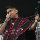 El rapero mexicano-triqui Carlos CGH, vestido con un gabán negro y rojo, una prenda nativa del pueblo triqui en el oeste de Oaxaca, actúa durante una celebración de los pueblos indígenas en el Zócalo de la Ciudad de México, el martes 6 de agosto de 2024. (Foto AP/Mariana Martínez Barba)