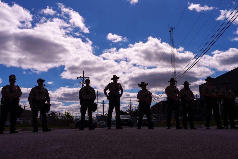 ARCHIVO - Agentes de la policía estatal de Illinois hacen guardia mientras un grupo de personas, incluyendo miembros de la Coalition for Spiritual and Public Leadership (CSPL), se congregan en el exterior de un centro del Servicio de Control de Inmigración y Aduanas en Broadview, Illinois, el 11 de octubre de 2025. (AP Foto/Adam Gray, archivo)