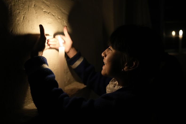 Samantha Alcívar juega con una vela en la panadería de sus padres durante un apagón eléctrico por racionamiento en Quito, Ecuador, el martes 15 de octubre de 2024. (AP Foto/Dolores Ochoa)