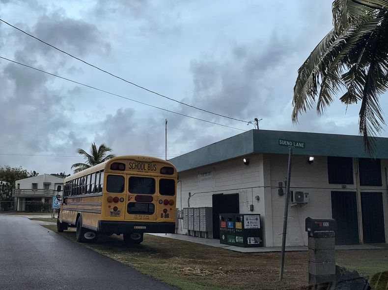 Un autobús escolar aguarda afuera del centro comunitario Mongmong-Toto-Maite para que traslade a habitantes a escuelas públicas convertidas en albergues de emergencia en Guam, el martes 23 de mayo de 2023, previo a la llegada del supertifón Mawar. (AP Foto/Grace Garces Bordallo)