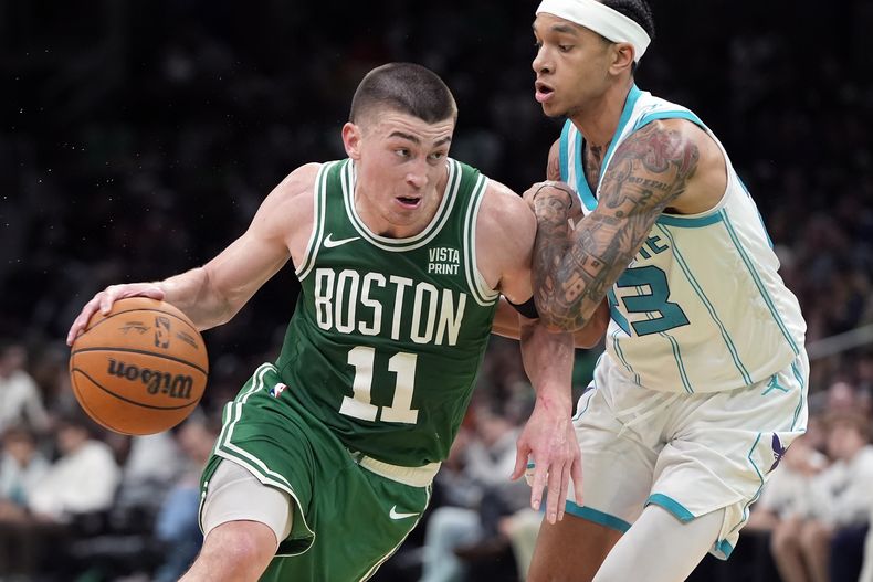 Payton Pritchard, de los Celtics de Boston, elude a Tre Mann, de los Hornets de Charlotte, durante el encuentro del viernes 12 de abril de 2024 (AP Foto/Michael Dwyer)