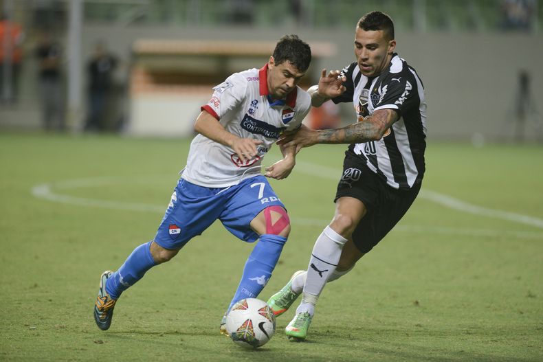 Nicol&aacute;s Otamendi del Atl&eacute;tico Mineiro de Brasil (derecha) disputa un bal&oacute;n con Juli&aacute;n Ben&iacute;tez del Nacional de Paraguay en la Copa Libertadores el mi&eacute;rcoles 19 de marzo de 2014. (AP Foto/Eugenio Savio)