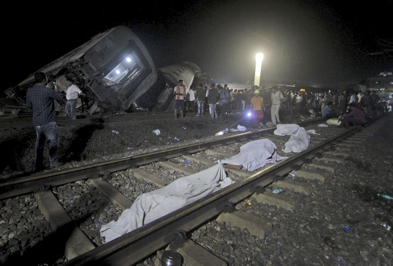 Numerosos cadáveres cubiertos permanecen a un lado de las vías, el sábado 3 de junio de 2023, cerca de donde se descarrilaron dos trenes de pasajeros en el distrito de Balasore, estado de Odisha, en el este de India. (AP Foto)