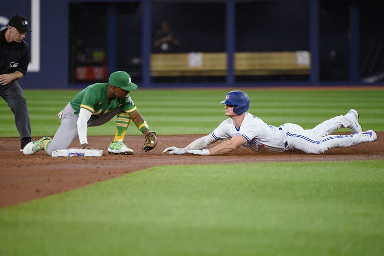 El segunda base de los Atléticos de Oakland, Tony Kemp, a la izquierda, pone out a Matt Chapman (26), de los Azulejos de Toronto, en la segunda entrada del partido en Toronto, el viernes 23 de junio de 2023. (Christopher Katsarov/The Canadian Press vía AP)