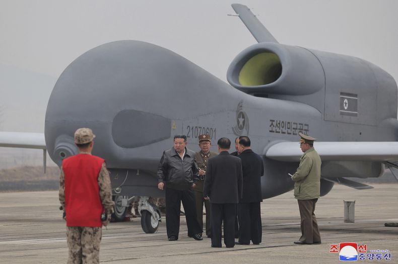 En esta foto proporcionada el jueves 27 de marzo de 2025 por el gobierno norcoreano, su líder, Kim Jong Un, e el centro con chaqueta negra, se ve junto a lo que parece ser un gran dron de reconocimiento en un lugar no revelado de Corea del Norte esta semana. Los periodistas independientes no recibieron acceso a cubrir el evento mostrado en esta imagen publicada por el gobierno norcoreano. La marca de agua es de la Agencia Central de Noticias de Corea. (Agencia Central de Noticias de Corea/Servicio de Noticias de Corea via AP)