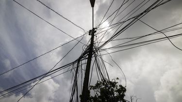 ARCHIVO - Un poste con cableado eléctrico se alza frente a una casa el 15 de septiembre de 2022, en Loiza, Puerto Rico. (AP Foto/Alejandro Granadillo, archivo)