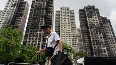 ARCHIVO - Una persona pasa ante torres residenciales destruidas por el fuego en el complejo de apartamentos Wang Fuk Court tras un incendio en noviembre, en el distrito de Tai Po de Hong Kong, el 20 de abril de 2026. (AP Foto/Chan Long Hei, Archivo)