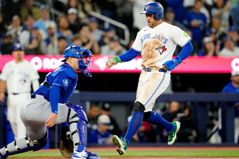 George Springer (derecha) de los Azulejos de Toronto anota una carrera ante los Dodgers de Los Ángeles, el lunes 6 de abril de 2026, en Toronto. (Frank Gunn/The Canadian Press vía AP)