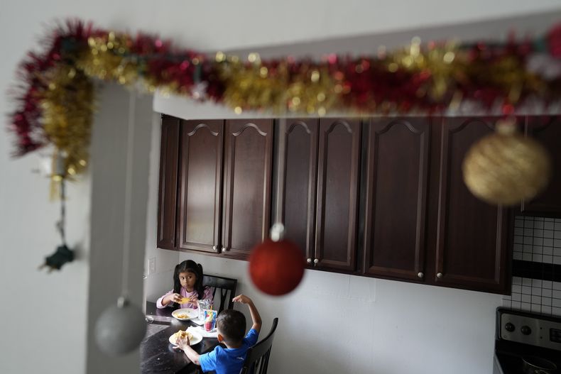 Alexa Llanos, de 7 años, almuerza junto a su hermano Alexis, de 3, en la casa de Lehigh Acres, en Florida, a la que se mudaron en octubre de 2023, cinco años después de haber salido de Venezuela hacia Colombia por amenazas de muerte, el 27 de diciembre de 2023. La de Llanos es una de las primeras familias de migrantes que llegaron a Estados Unidos legalmente bajo un nuevo programa conocido como Oficinas de Movilidad Segura, que busca agilizar el proceso de refugiados. (AP Foto/Rebecca Blackwell)