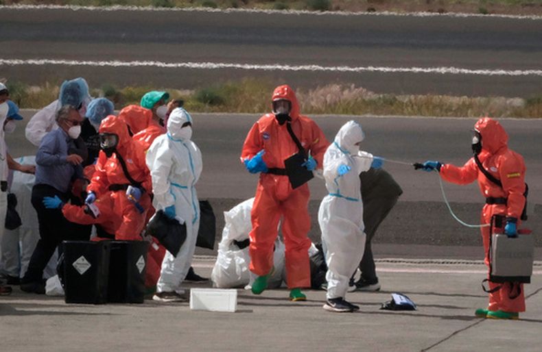 Personal de sanidad del gobierno español desinfecta a pasajeros tras desembarcar del crucero afectado por un brote de hantavirus, en el aeropuerto de Tenerife, en las islas Canarias, España, el 10 de mayo de 2026. (AP Foto/Arturo Rodríguez)