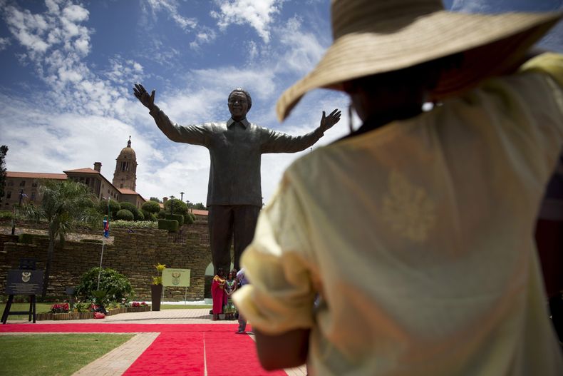 Una mujer observa una estatua de bronce de 9 metros del ex presidente sudafricano Nelson Mandela en Pretoria, el lunes 16 de diciembre del 2013. (AP Foto/Matt Dunham)