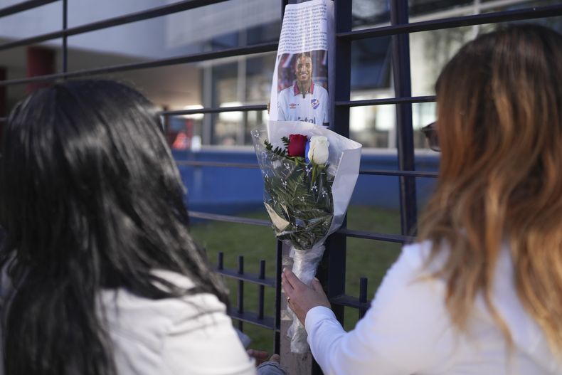 Aficionados colocan un ramo de flores ante un foto del futbolista uruguayo Juan Izquierdo en la sede del club Nacional, el miércoles 28 de agosto de 2024, en Montevideo. Izquierdo falleció el martes en un hospital de Brasil, cinco días después de colapsar durante un partido de la Copa Libertadores. (AP Foto/Matilde Campodónico)