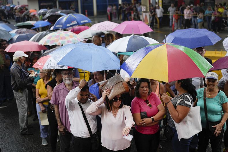 Personas hacen fila en medio de una fuerte lluvia para votar en las elecciones primarias de la oposición en Caracas, Venezuela, el domingo 22 de octubre de 2023. La oposición elegirá un candidato para desafiar al presidente Nicolás Maduro en las elecciones presidenciales de 2024. (Foto AP/Matías Delacroix)